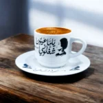 ⁦فنجان قهوه أم كلثوم بورسلين – تصميم كوبليه "ياما عيون شغلوني" – أبيض × أسود – 6×8 سم⁩ - الصورة ⁦2⁩