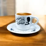 ⁦فنجان قهوه أم كلثوم بورسلين – تصميم كوبليه "ياما عيون شغلوني" – أبيض × أسود – 6×8 سم⁩ - الصورة ⁦4⁩