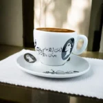 ⁦فنجان قهوة فيروز بورسلين بتصميم كوبليه “أنت الآساسي” – أبيض × أسود – شكل بيضاوي – سعة 90 مل⁩ - الصورة ⁦3⁩